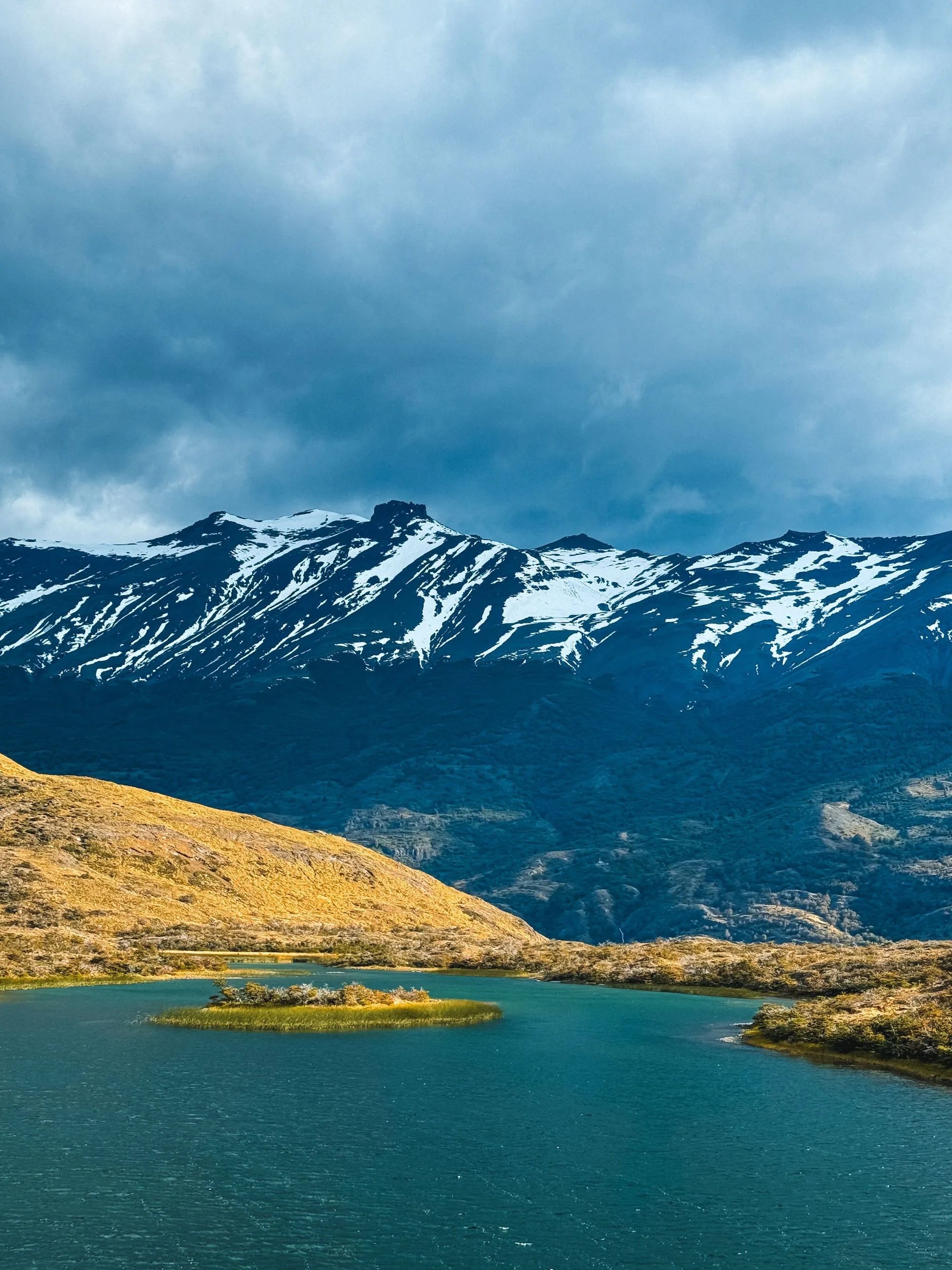 Lago de aguas turquesa rodeado de cerros con nieve en la Patagonia.
